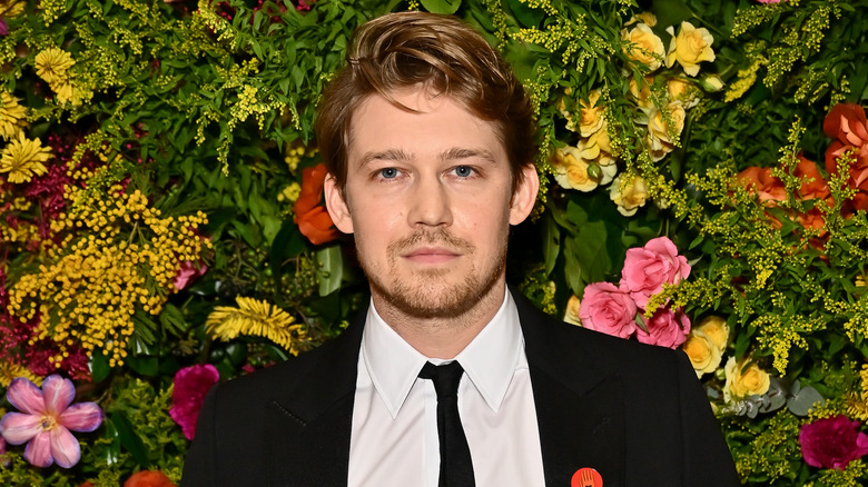 Joe Alwyn posa davanti a un muro di fiori