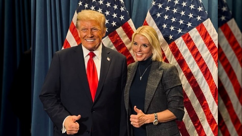 Donald Trump e Pam Bondi alzano il pollice davanti ad alcune bandiere americane