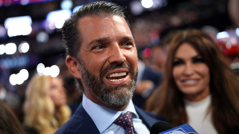 Donald Trump Jr. parla ai media alla RNC con Kimberly Guilfoyle dietro di lui