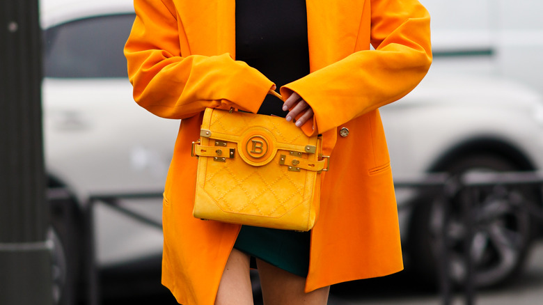 Donna con blazer oversize arancione e borsa con logo