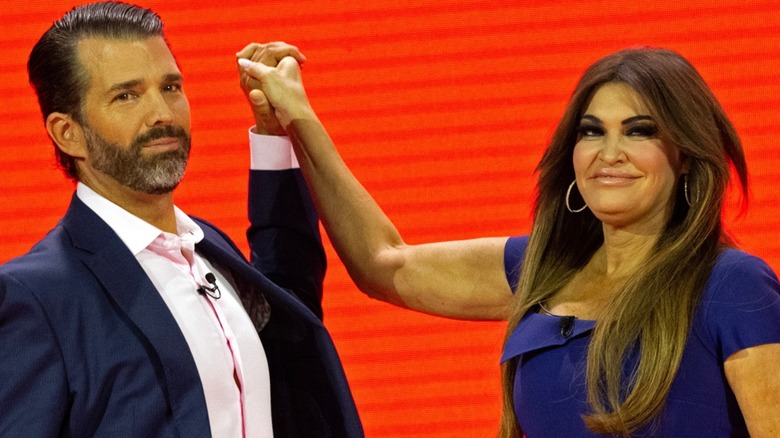 Donald Trump Jr. e Kimberly Guilfoyle sul palco tenendosi per mano in aria