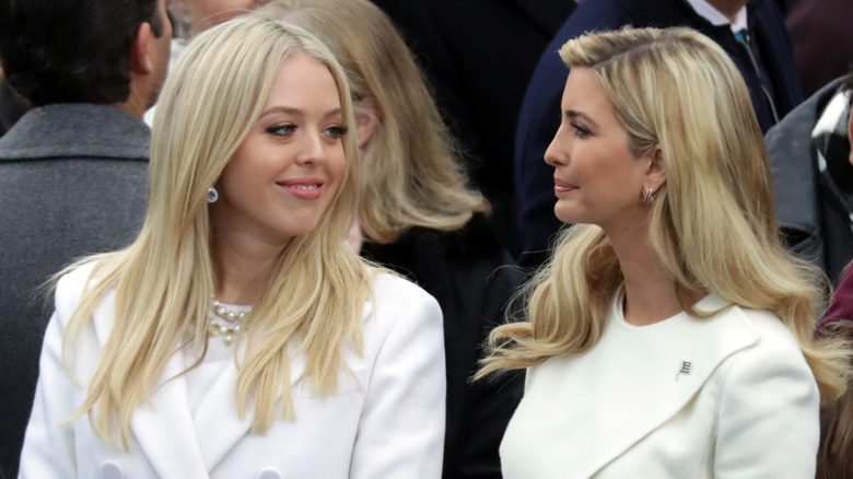 Tiffany Trump sorride a Ivanka Trump mentre la sorella maggiore le dà una pacca sul braccio durante l'inaugurazione di Donald Trump.