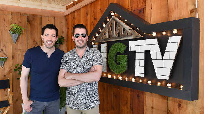 Drew Scott e Jonathan Scott posano accanto al cartello HGTV