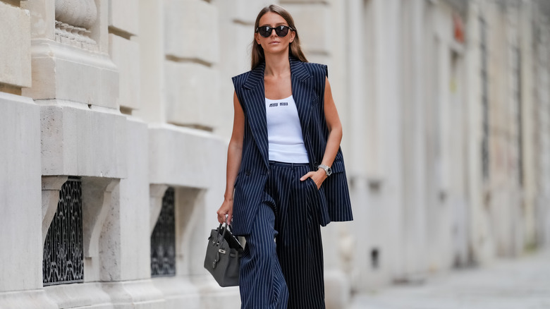 Una donna che indossa pantaloni a righe e un blazer.